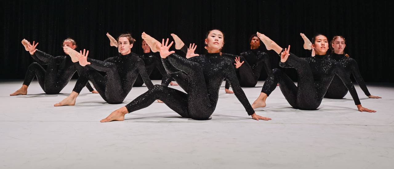 Dancers in black sequin costumes legs in air
