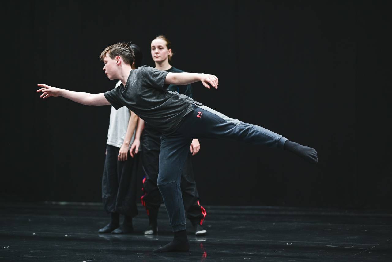 young male presenting dancer balances on one leg
