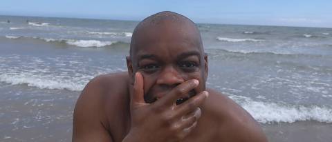 Marvin standing with hand over mouth, sea behind him