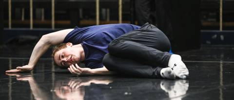 dancer in blue tshirt laying on floor