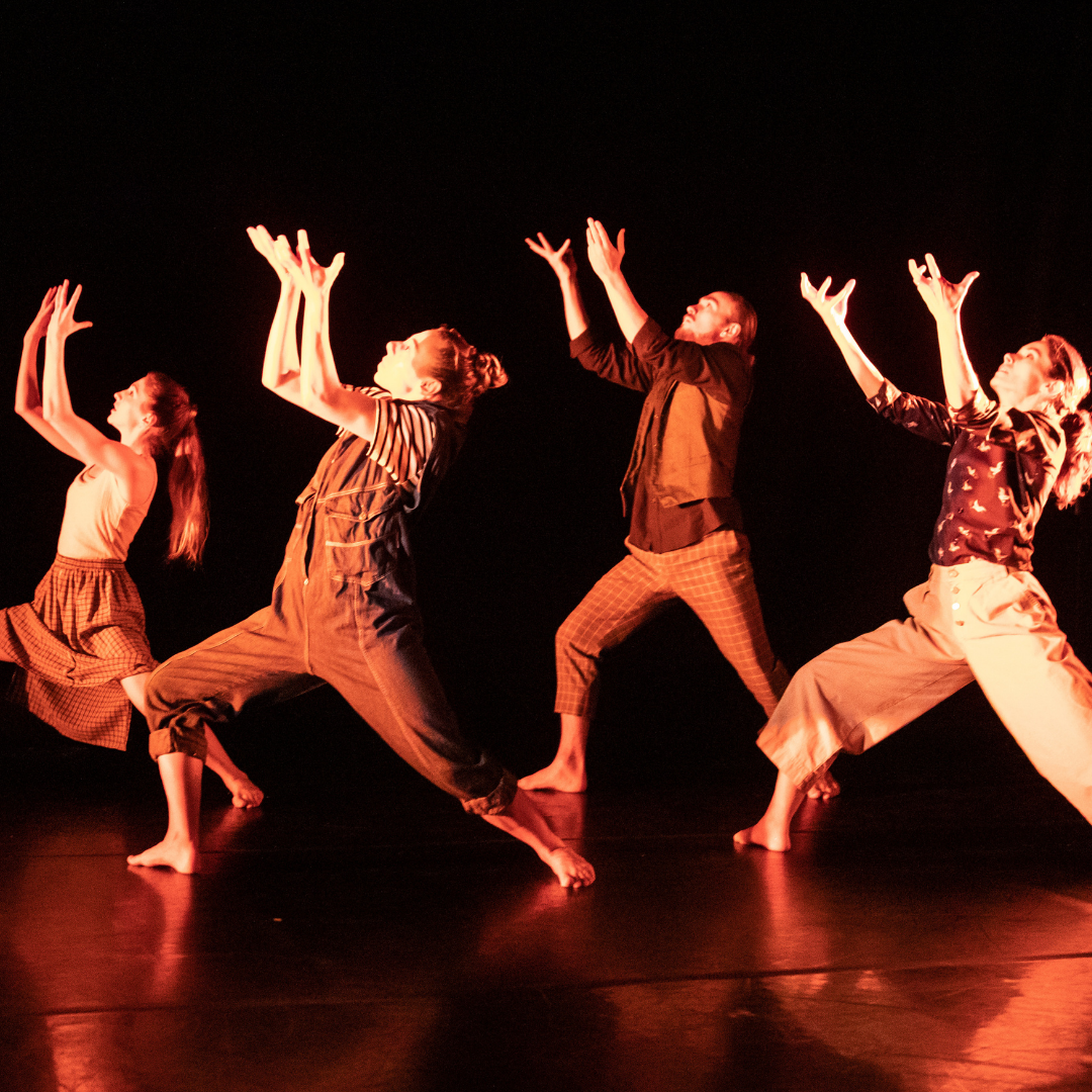 dancers under red lights lifting their arms to the sky