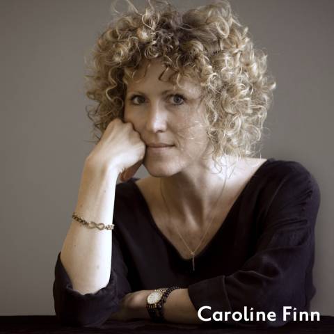 Caroline finn rests her cheek on her first, she looks intensely at the camera 