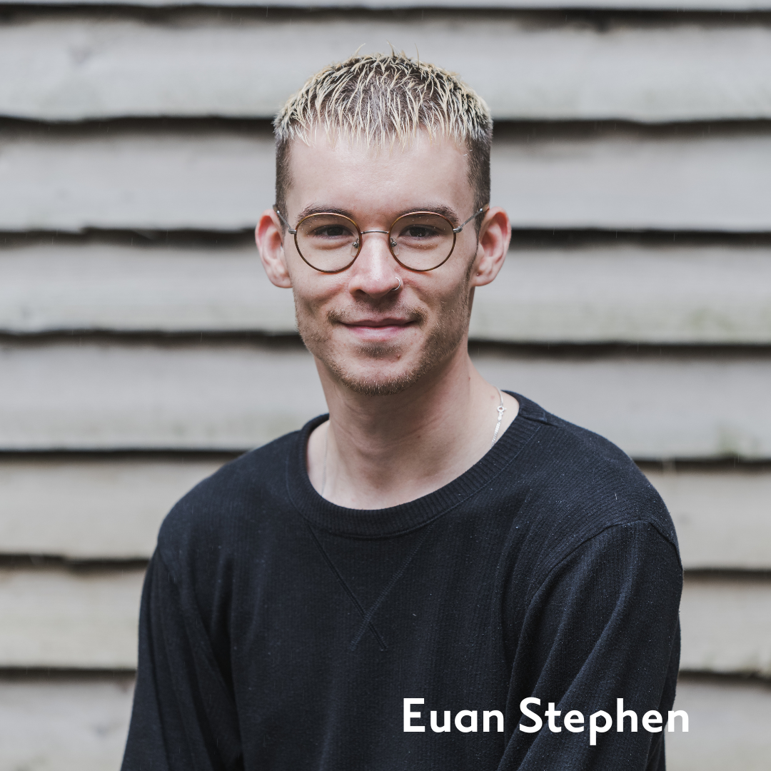 Euan smiles in glasses and a black shirt
