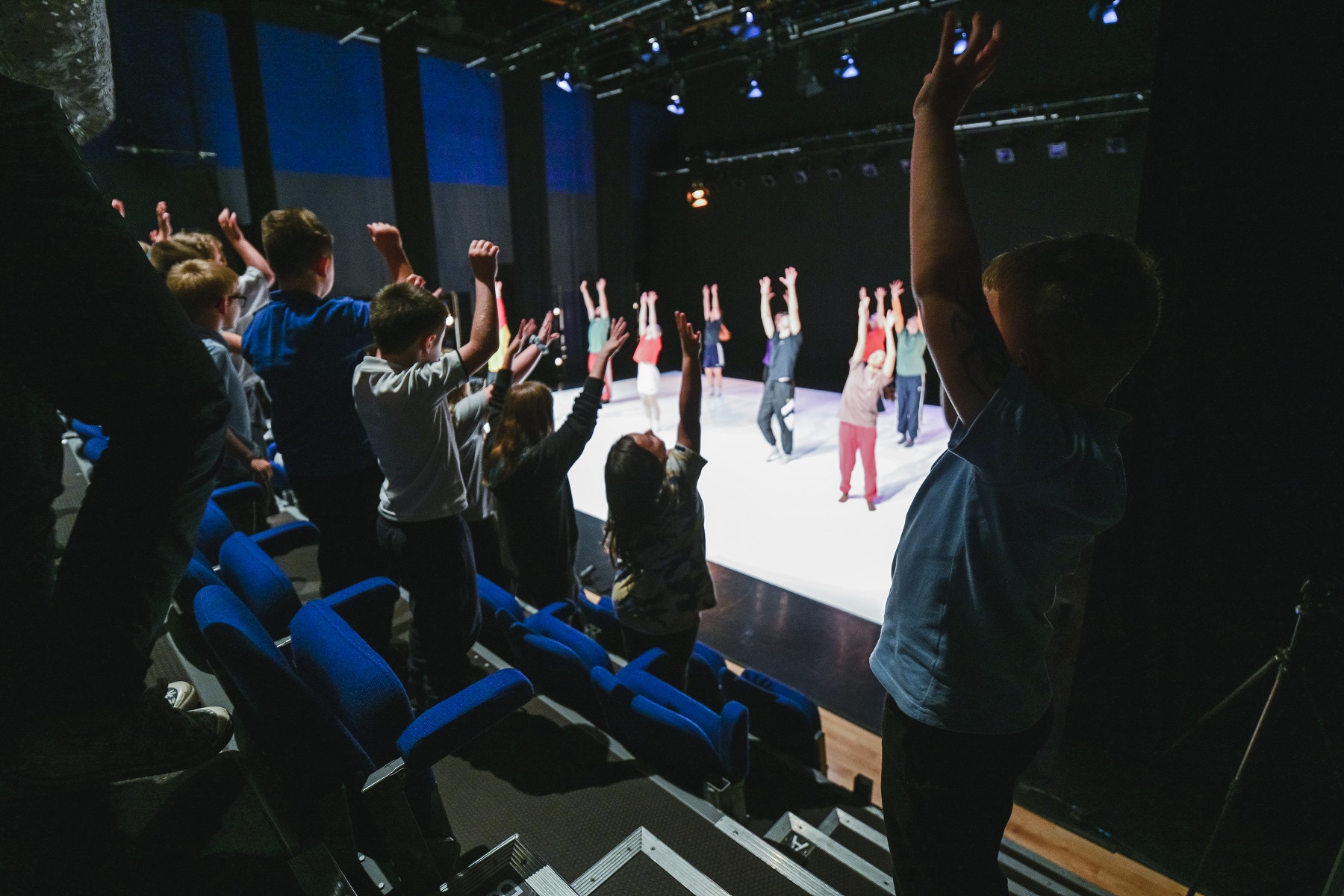children stretch from their seats whilst our dancers on stage show them how