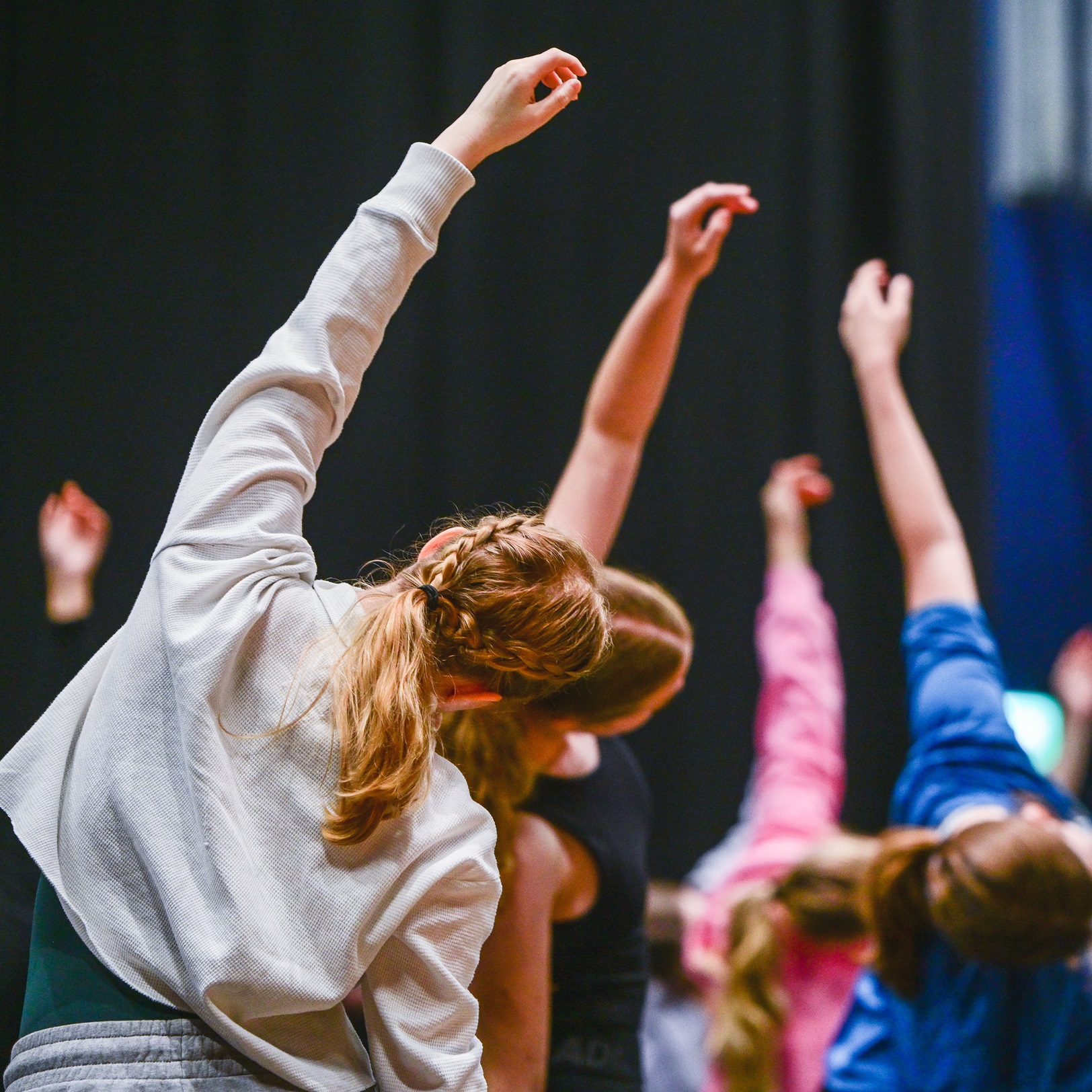 young dancers stretching their arms to the sky in a yoga like stretch