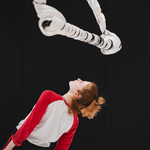 a dancer leans backwards as a swinging sculpture narowly misses her head