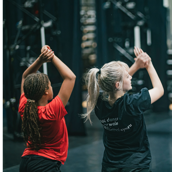 two young dancers in the ndcwales studio, arms in the air learning choreography