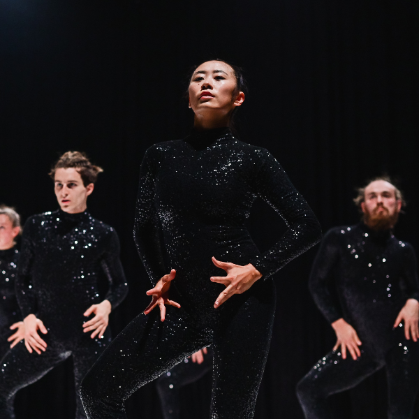 dancers in black sequin costumes pose with strong, stretched out hands