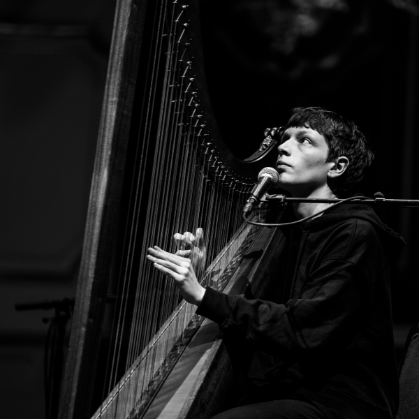 black and white photo of Cerys playing their harp