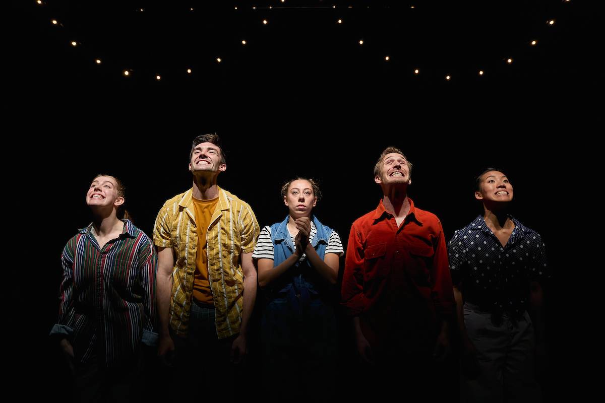 5 dancers stand together in bright shirts and pull faces whilst under a spotlight