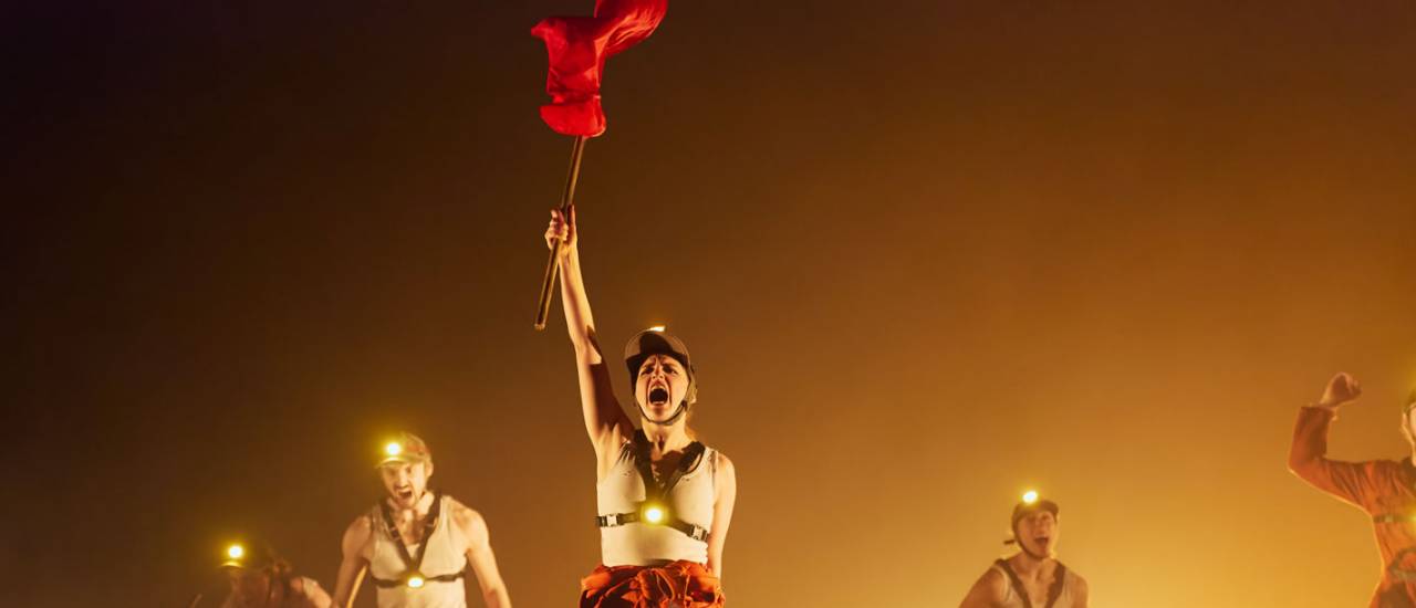 Photo of dancer holding a red flag in the air