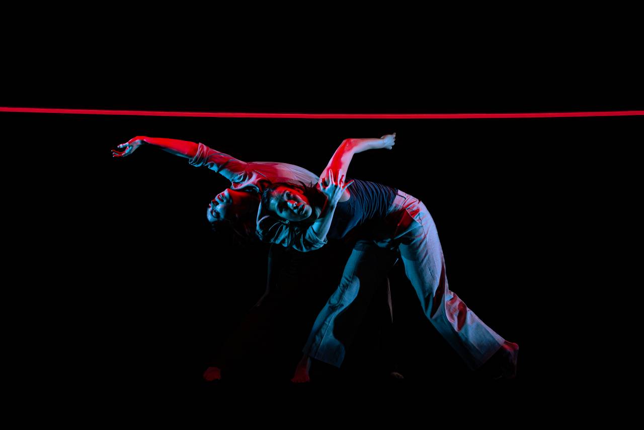 two dancers under a neon blue and red light 