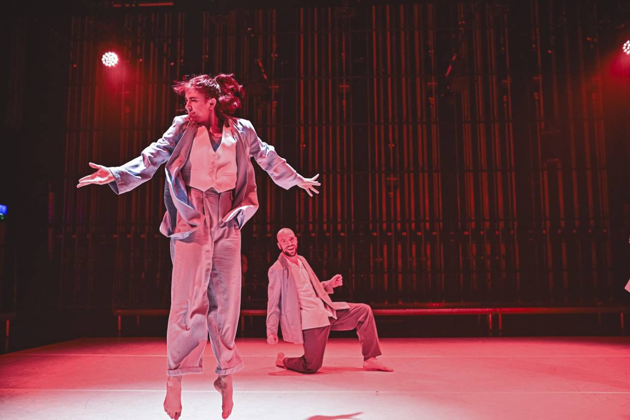 Niamh leaps arms outstretched under a red light