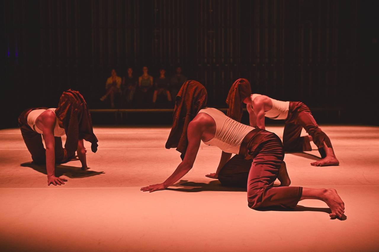 dancers crawling around stage with heads covered in shirts