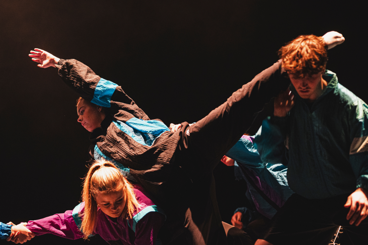 young dancers in performance under warm lights wearing retro sheellsuit jackets