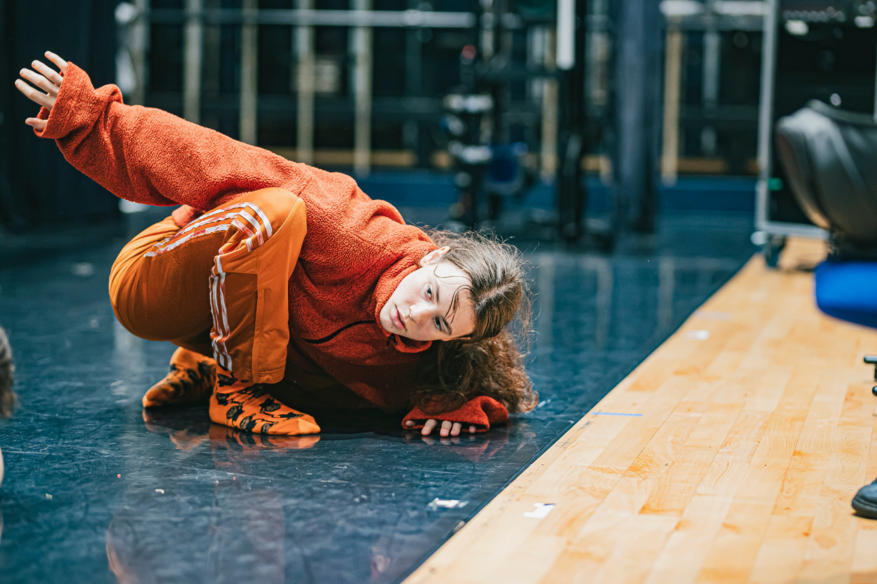 a young dancer dressed in oraange rehearsal clothes