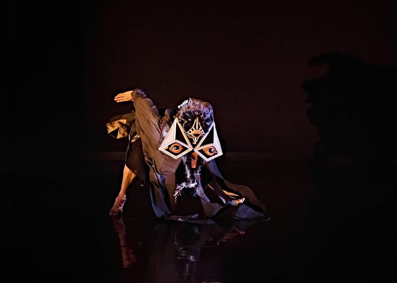 Jason in a blackbird mask and large cloak crouched low to the ground