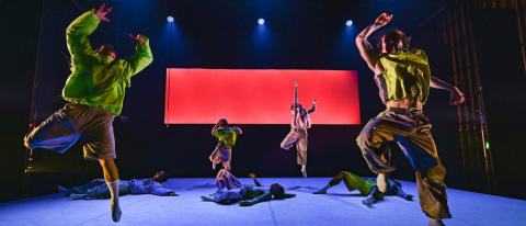 dancers in neon green leaping across a red backdrop