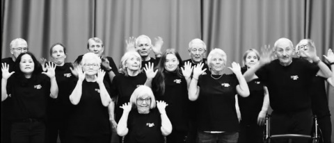 dance for parkinsons cardiff class in black and white making jazz hands and a shocked face towards the camera