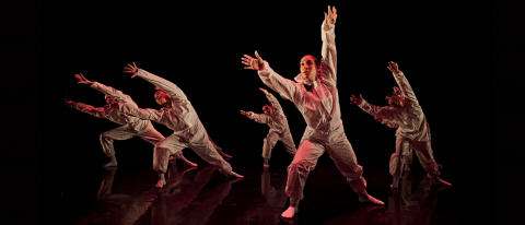 young dancers in white overalls under red light