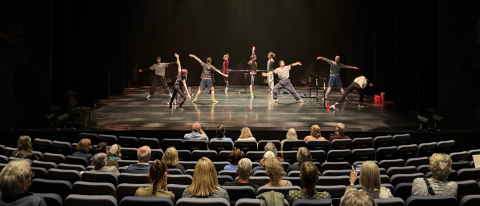 dancers warm up on stage whilst people watch