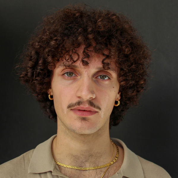 Pietro has curly hair that falls to his wears and nape, a pencil moustache and a smokey expression - he wears gold earrings and necklaces