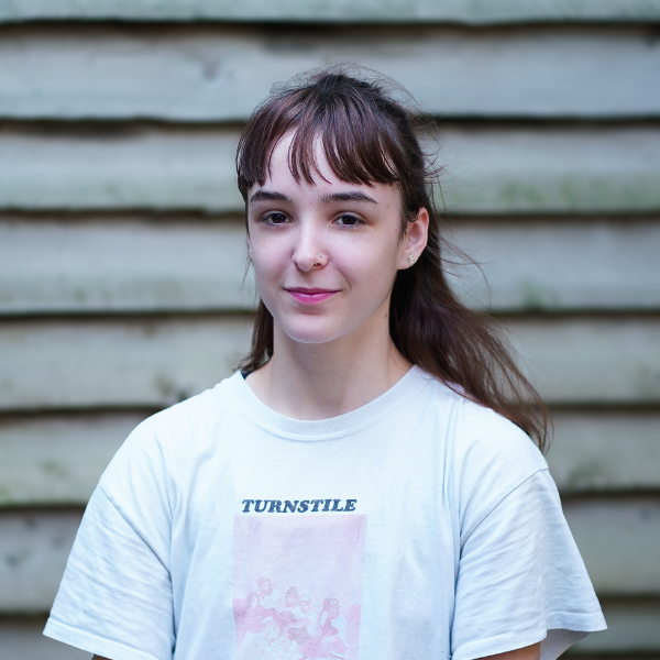 Isabella has brown hair that reaches the shoulders and a fringe, Bella wears a white t shirt with a pink logo